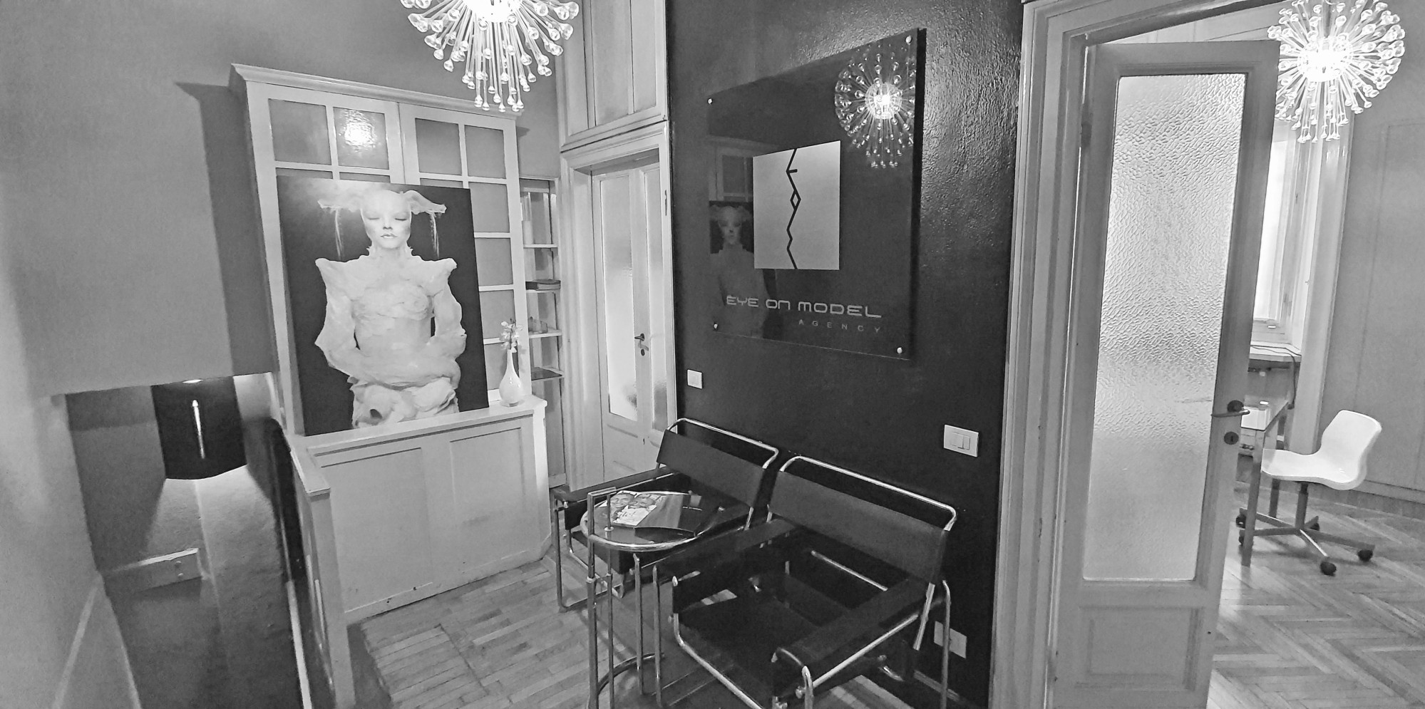 Area reception di Eye On Model con scultura classica e logo dell’agenzia nella sede di Milano